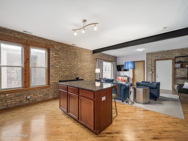 kitchen featuring light wood-type flooring, visible vents, and brick wall