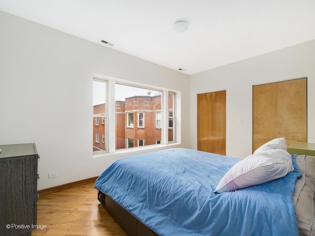 bedroom featuring baseboards, visible vents, and wood finished floors