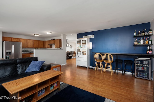 living area with a bar, wood finished floors, wine cooler, and baseboards