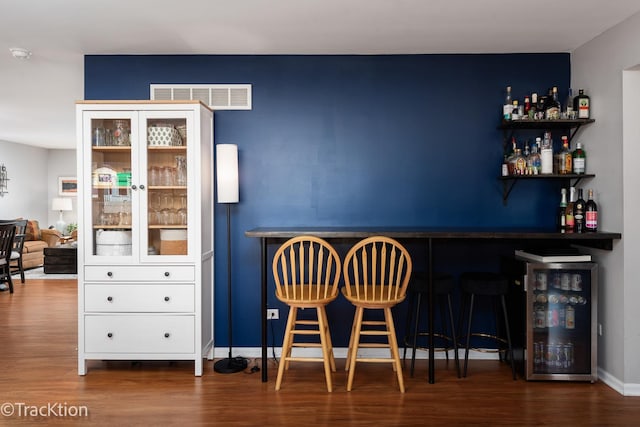 indoor dry bar featuring wood finished floors, beverage cooler, and baseboards