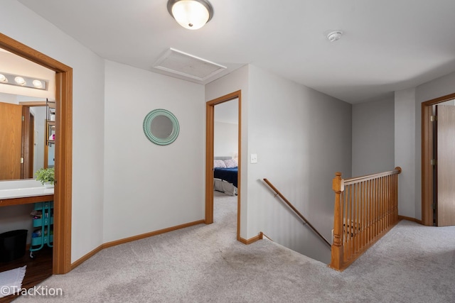 hallway featuring an upstairs landing, attic access, carpet, and baseboards