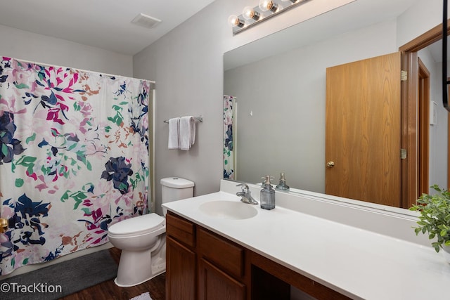 bathroom featuring toilet, wood finished floors, vanity, and curtained shower