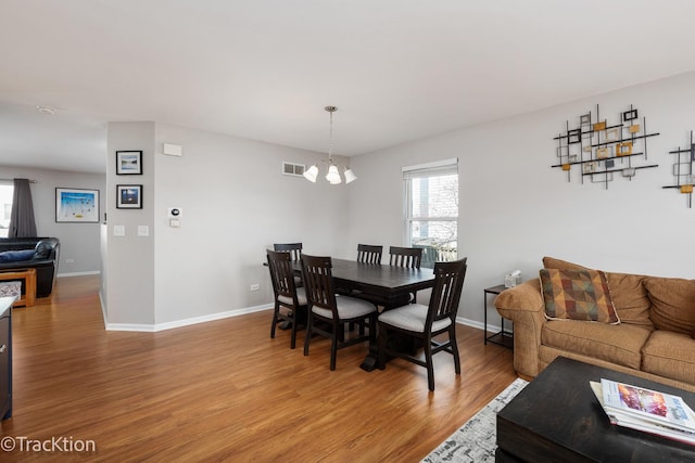 dining space featuring plenty of natural light, light wood-style floors, a chandelier, and baseboards