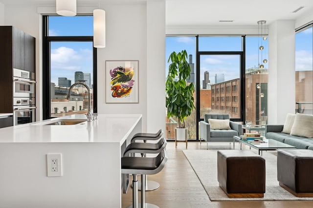 interior space featuring wood finished floors, a sink, a city view, light countertops, and floor to ceiling windows