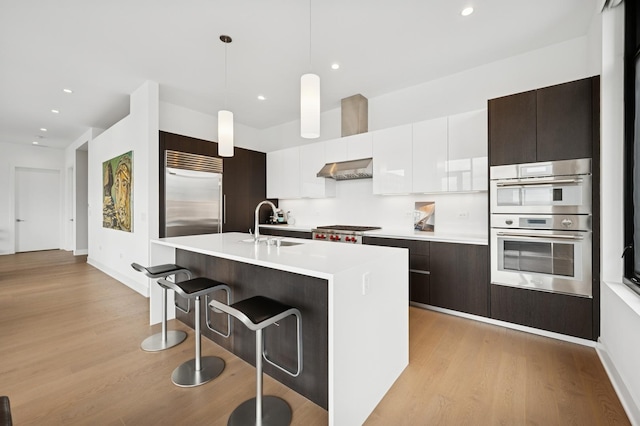 kitchen with light countertops, appliances with stainless steel finishes, a breakfast bar, and light wood-style floors