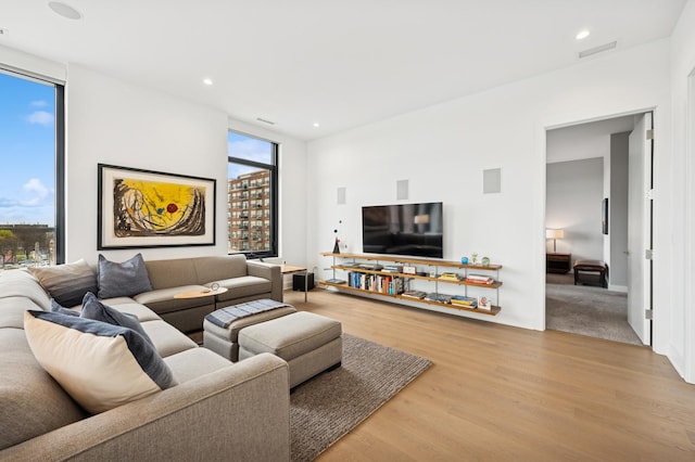 living room with recessed lighting, visible vents, and wood finished floors