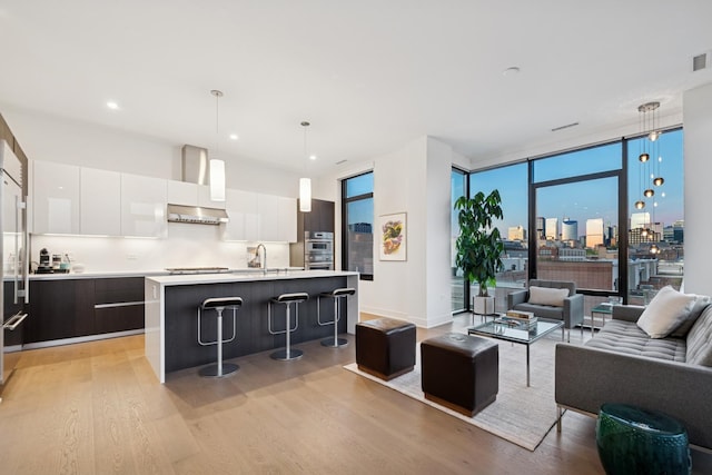 living room featuring visible vents, recessed lighting, light wood-style flooring, a city view, and a wall of windows