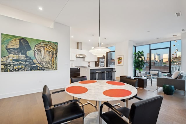 dining area with light wood-style floors, visible vents, baseboards, and expansive windows