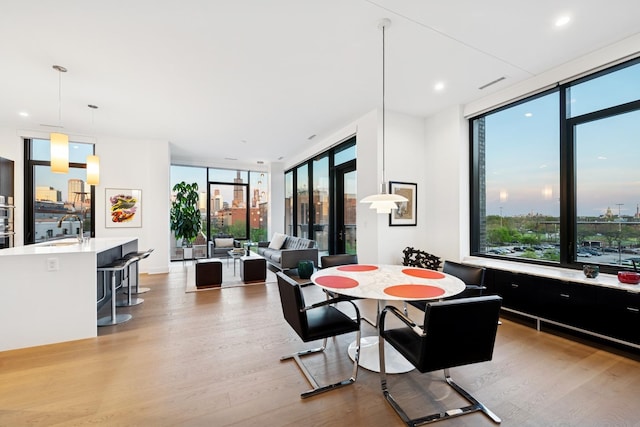 dining room featuring recessed lighting, floor to ceiling windows, and light wood-style floors