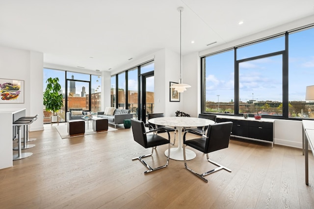 dining space featuring light wood finished floors and expansive windows