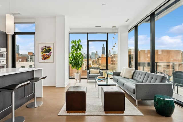 living area with a city view, a wealth of natural light, visible vents, and wood finished floors