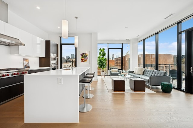 kitchen featuring stainless steel gas stovetop, modern cabinets, a sink, white cabinetry, and light countertops