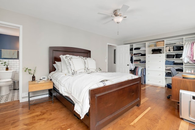 bedroom featuring light wood-type flooring, ensuite bathroom, and a ceiling fan