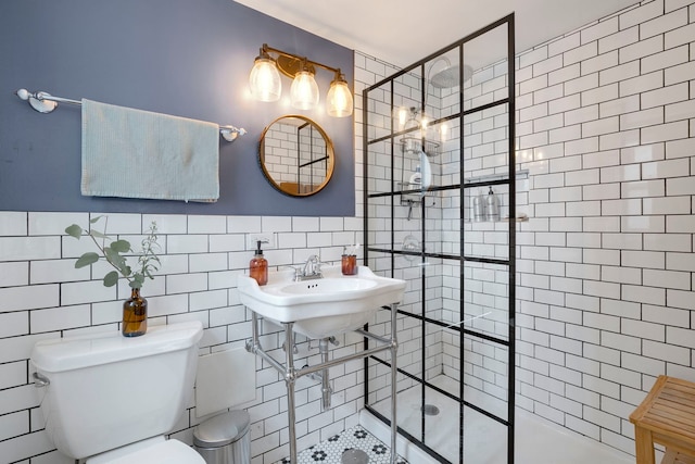 bathroom with tile walls, a stall shower, toilet, and wainscoting