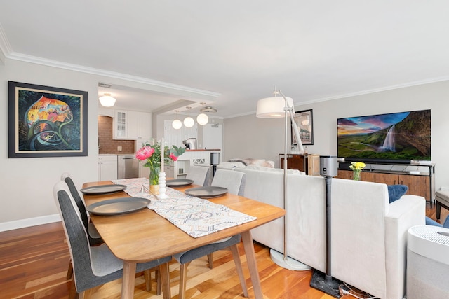 dining area with crown molding, light wood-style flooring, and baseboards