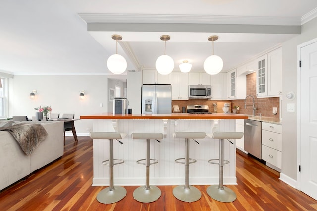kitchen featuring appliances with stainless steel finishes, dark wood-style flooring, light countertops, and ornamental molding