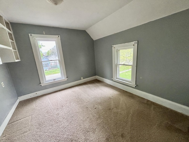 bonus room with vaulted ceiling, carpet floors, baseboards, and a healthy amount of sunlight