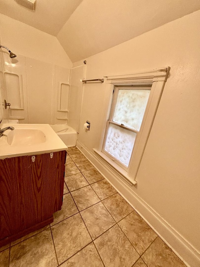 full bathroom with vanity, tile patterned floors, vaulted ceiling, bathing tub / shower combination, and baseboards