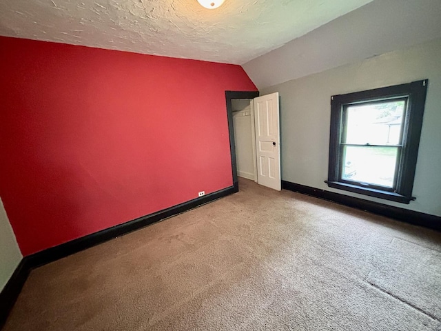 interior space with carpet flooring, vaulted ceiling, and baseboards