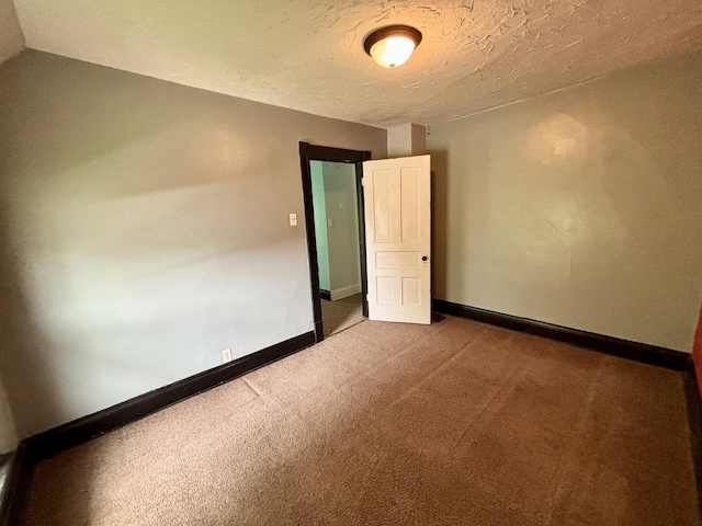 empty room featuring baseboards, a textured ceiling, and carpet floors