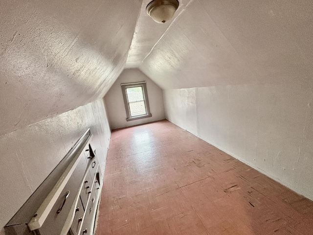 additional living space featuring lofted ceiling and a textured ceiling