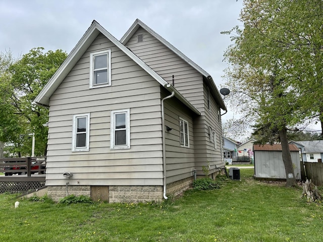 view of side of property featuring a yard, an outdoor structure, a shed, central AC, and a deck
