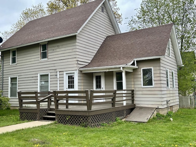 rear view of property featuring a yard, roof with shingles, and a wooden deck