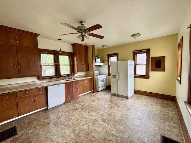 kitchen with a sink, white appliances, a ceiling fan, and plenty of natural light