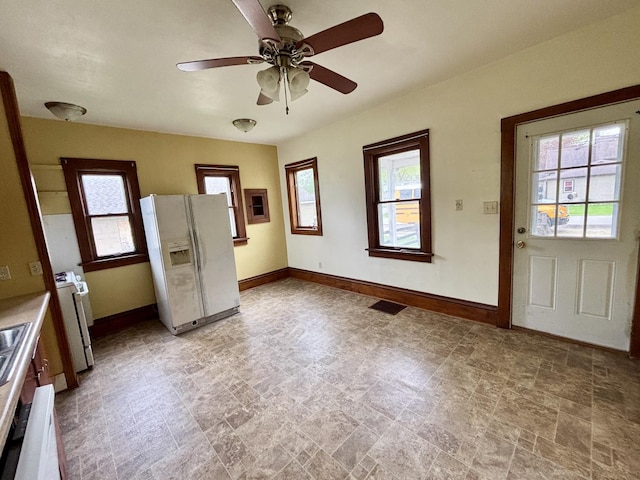 interior space featuring baseboards, a wealth of natural light, stone finish floor, and a ceiling fan
