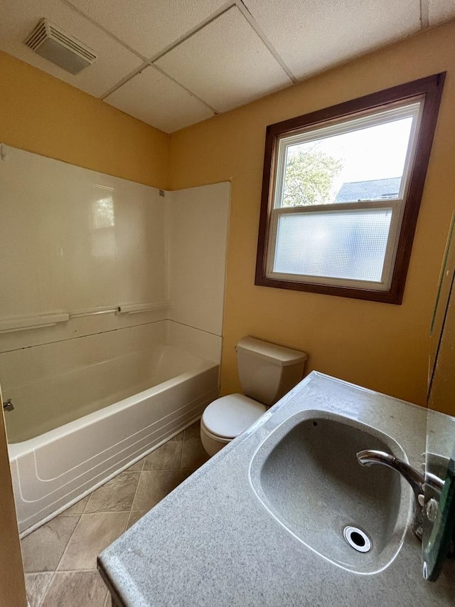 bathroom with a sink, toilet, visible vents, tile patterned floors, and a paneled ceiling
