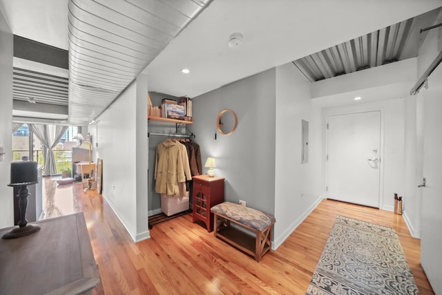 corridor featuring electric panel, wood finished floors, baseboards, and recessed lighting