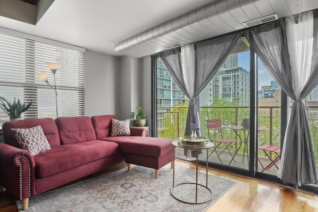 living area with plenty of natural light, visible vents, wood finished floors, and a view of city
