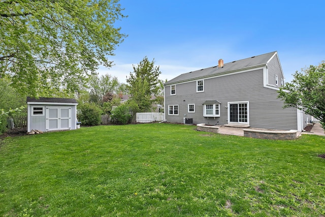 rear view of property with a shed, a patio, an outdoor structure, a chimney, and central AC unit