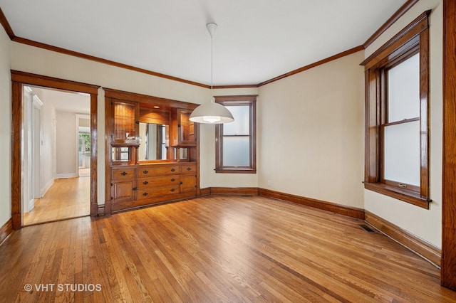 spare room featuring light wood-style floors, baseboards, and ornamental molding