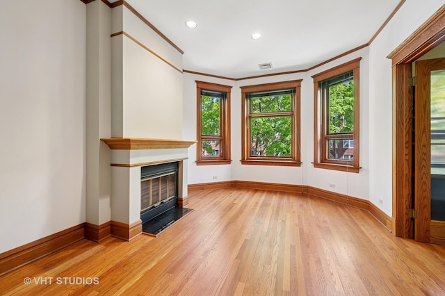 unfurnished living room with light wood-style flooring, baseboards, crown molding, a fireplace with flush hearth, and recessed lighting