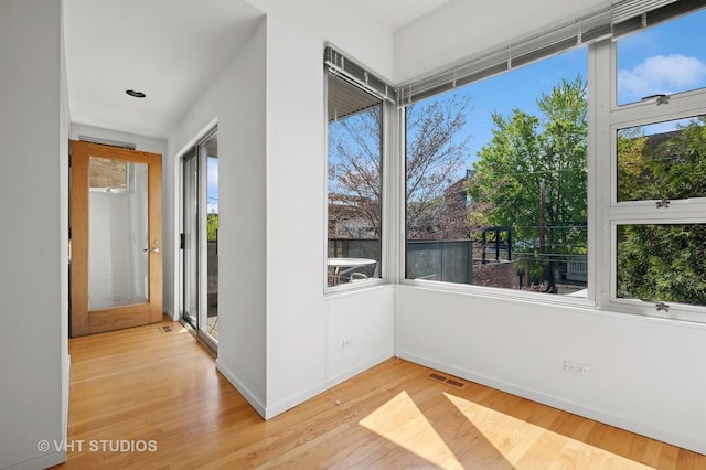unfurnished room with light wood-style floors, baseboards, and healthy amount of natural light