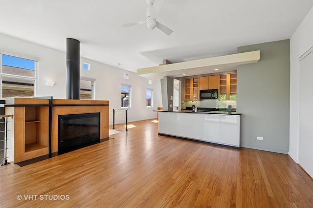 kitchen featuring black microwave, dark countertops, and light wood finished floors