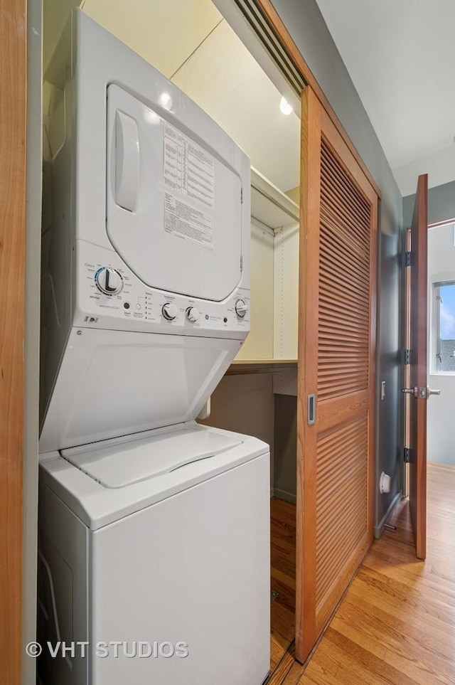 laundry room featuring stacked washing machine and dryer and light wood-type flooring