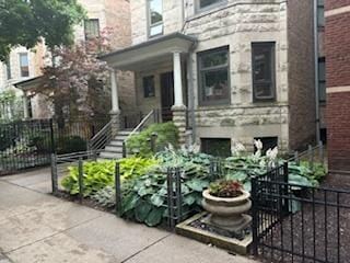 entrance to property with fence, stone siding, and a porch