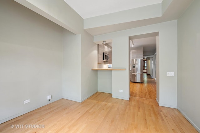 spare room with light wood-style floors and baseboards