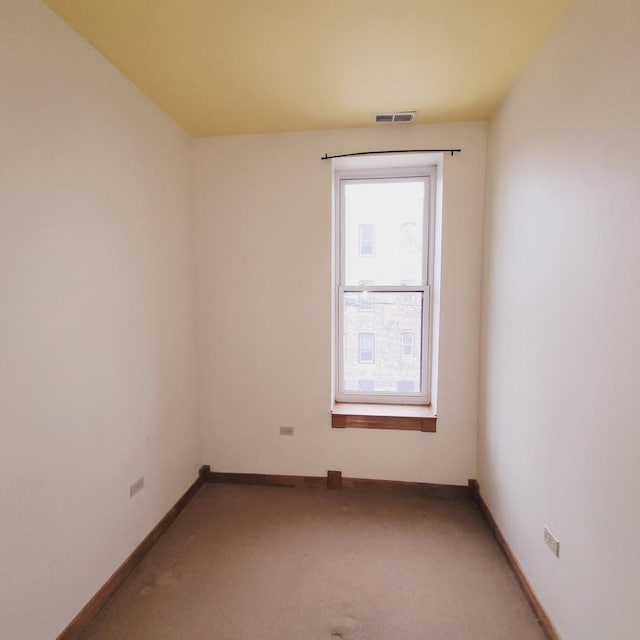 carpeted spare room featuring visible vents and baseboards