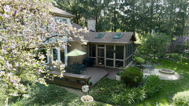 585 Apache Dr, Batavia, IL 60510 - back of property featuring an outdoor fire pit, a wooden deck, a sunroom, a chimney, and a shingled roof