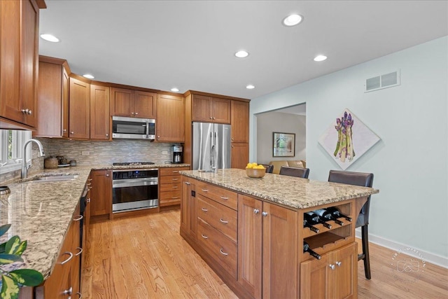 585 Apache Dr, Batavia, IL 60510 - kitchen with stainless steel appliances, a sink, light wood finished floors, a kitchen island, and tasteful backsplash
