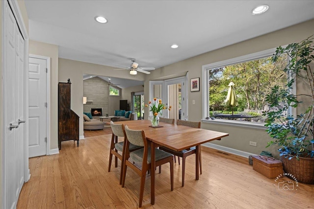585 Apache Dr, Batavia, IL 60510 - dining space with light wood-style floors, a fireplace, a ceiling fan, baseboards, and lofted ceiling