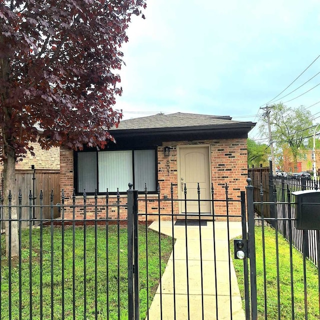 view of front facade featuring a fenced front yard, a front yard, brick siding, and a shingled roof