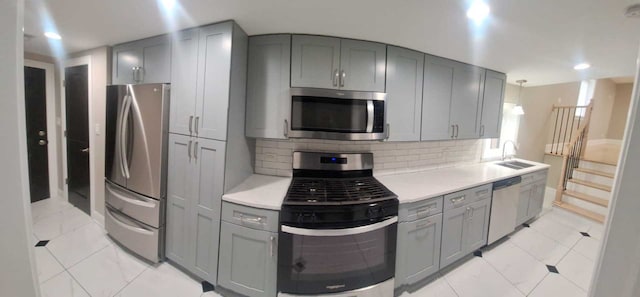 kitchen with a sink, gray cabinetry, light countertops, and appliances with stainless steel finishes