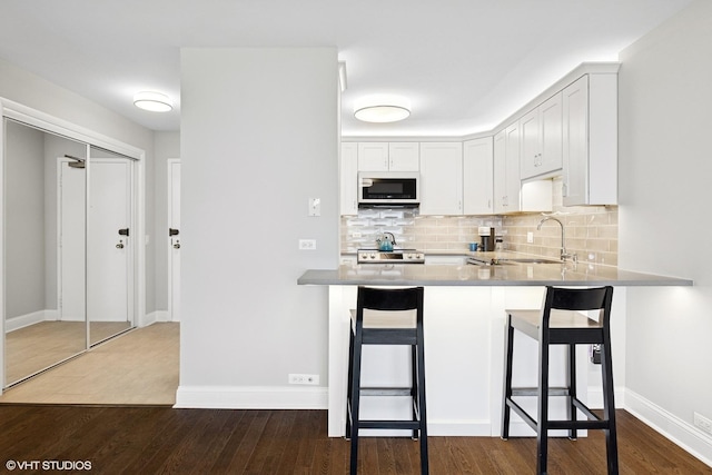 5415 N Sheridan Rd Unit 3004, Chicago, IL 60640 - kitchen with a sink, decorative backsplash, stainless steel electric range, dark wood-type flooring, and a breakfast bar area
