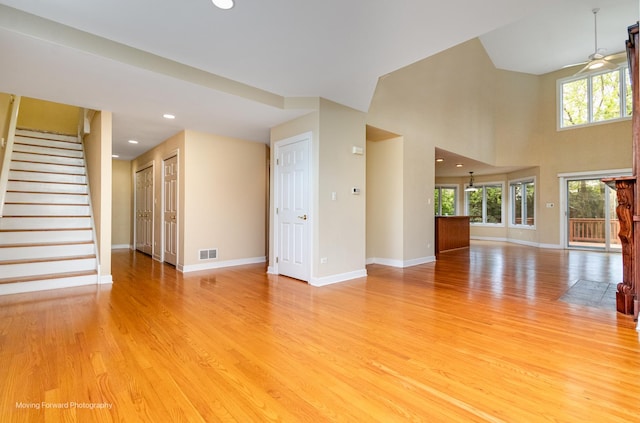 unfurnished living room with baseboards, ceiling fan, light wood-type flooring, stairs, and recessed lighting