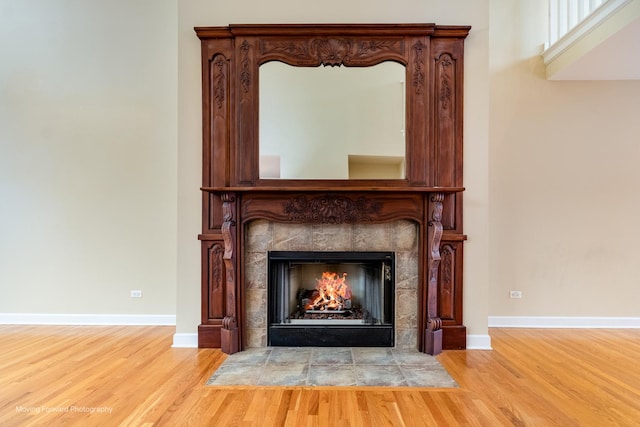 detailed view of wood finished floors, a fireplace, and baseboards