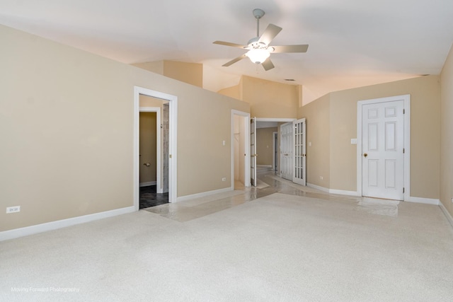 unfurnished bedroom with light colored carpet, baseboards, lofted ceiling, french doors, and ensuite bath